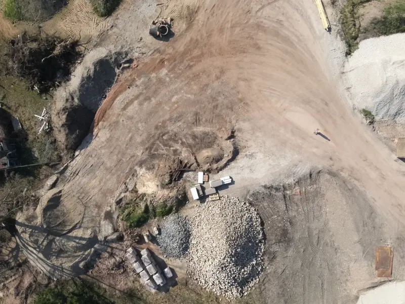 Erdbaustelle mit Böschung, Haufwerken und Fahrzeugen senkrecht von oben