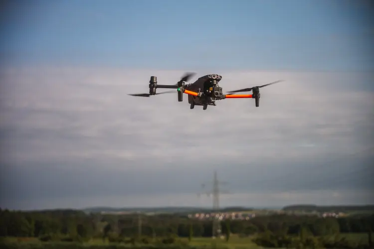 Drohne im Flug über einer Landschaft mit Strommasten