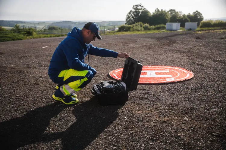 Pilot kniet am Einsatzkoffer neben dem Landeplatz auf einem Schotterplatz