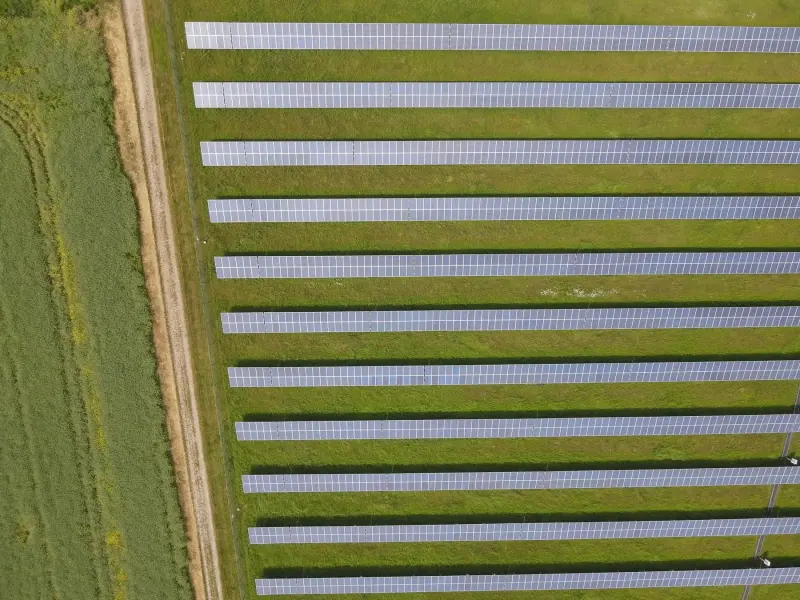 Freiflächen-Solarpark von oben, Modulreihen neben einem Feldweg