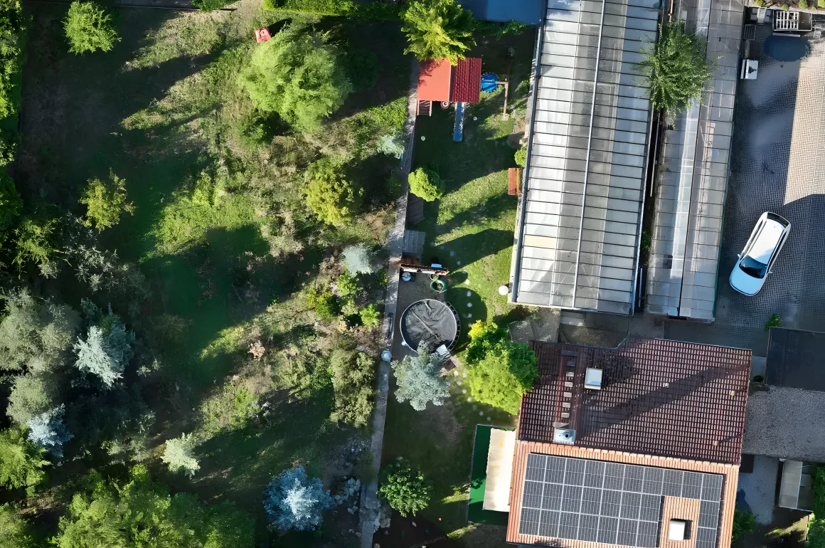 Orthofoto eines Gewerbegrundstücks mit Gewächshaus, Wohnhaus mit PV-Dach und Garten, aus Drohnenbildern zusammengesetzt
