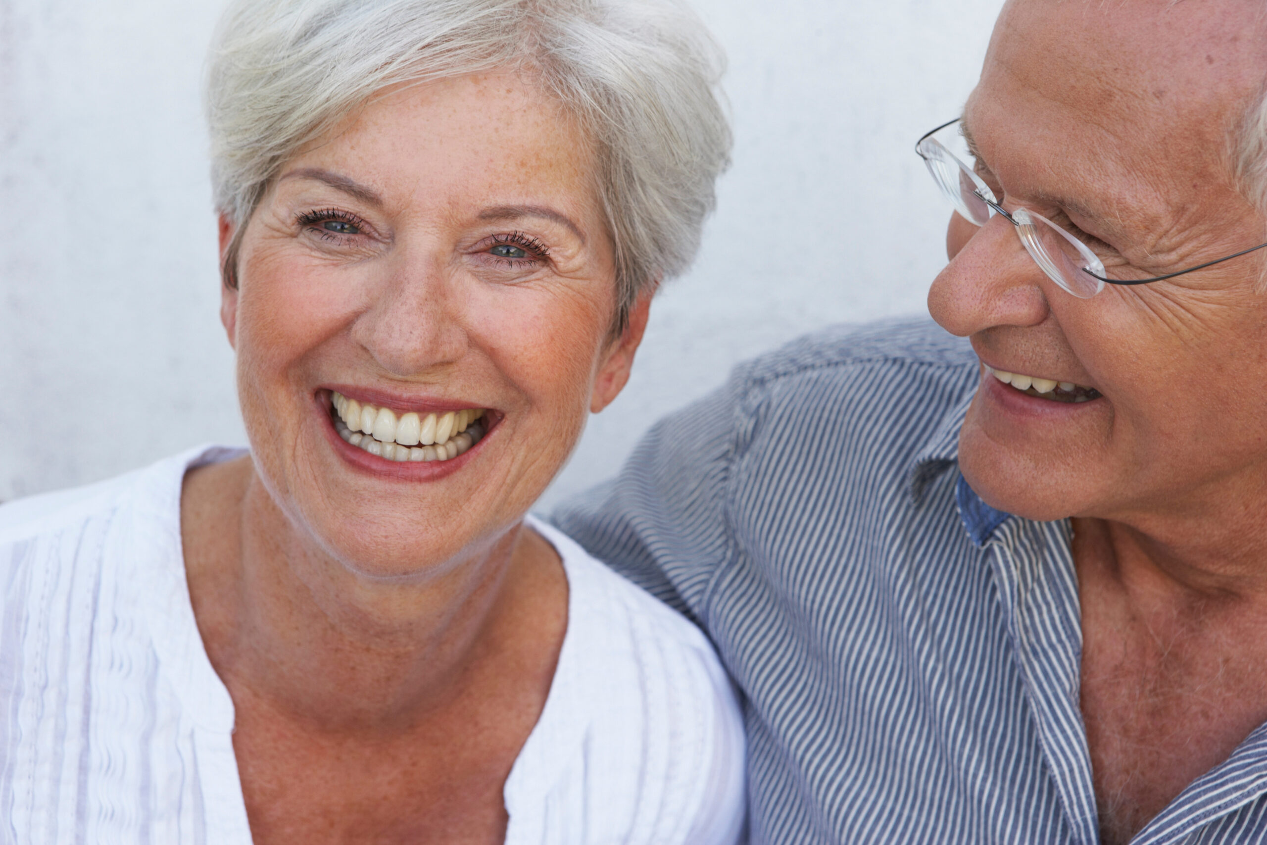 Lächelndes Seniorenpaar bei Beratung zum Zahnersatz